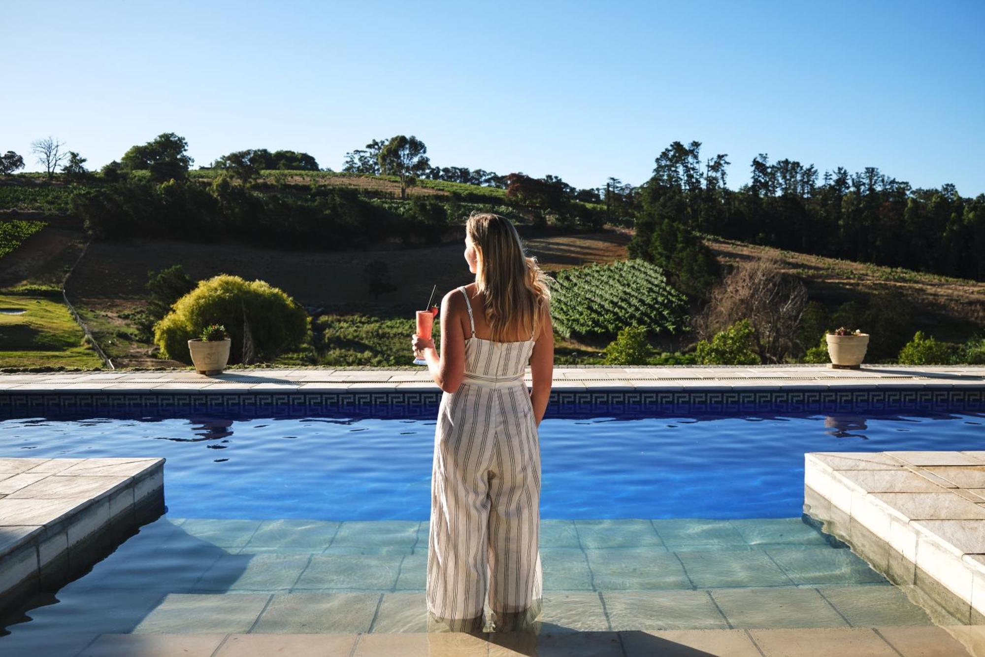 Alluvia Boutique Winery & Luxury Accommodation ステレンボッシュ 部屋 写真 A woman standing by a pool